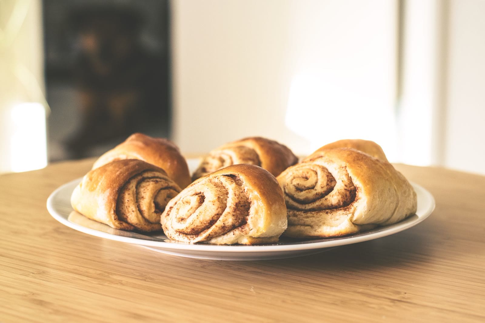 A plate of cinnamon rolls on a sunny table