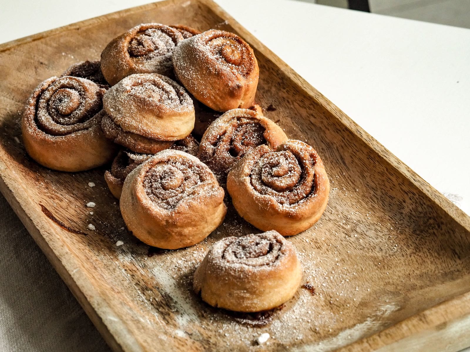 Cinnamon rolls dusted with sugar on a wooden tray