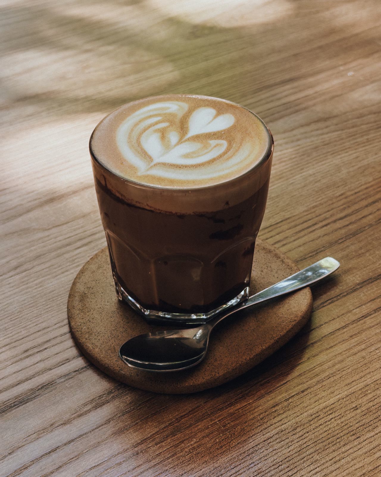 Latte in a glass on a wooden table in soft daylight