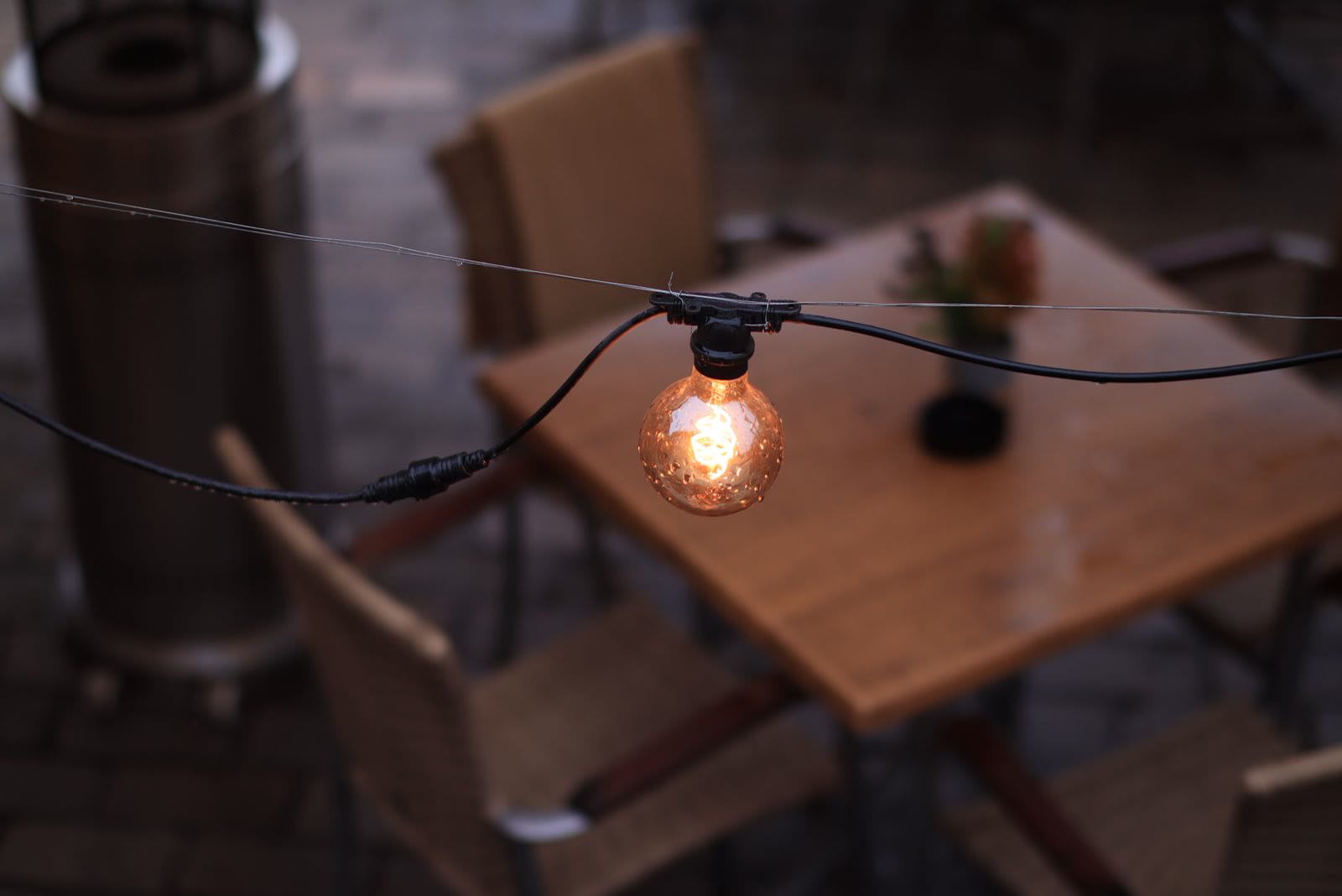 String light glowing over a wooden patio table