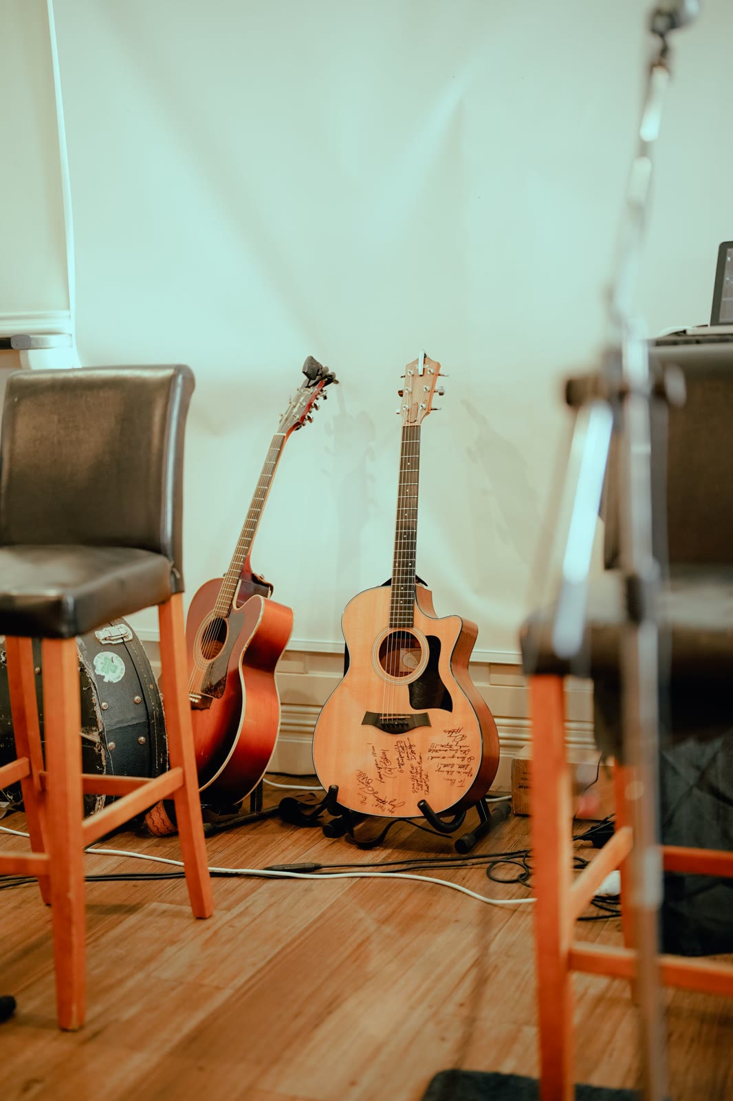 Two acoustic guitars on stands on a small stage