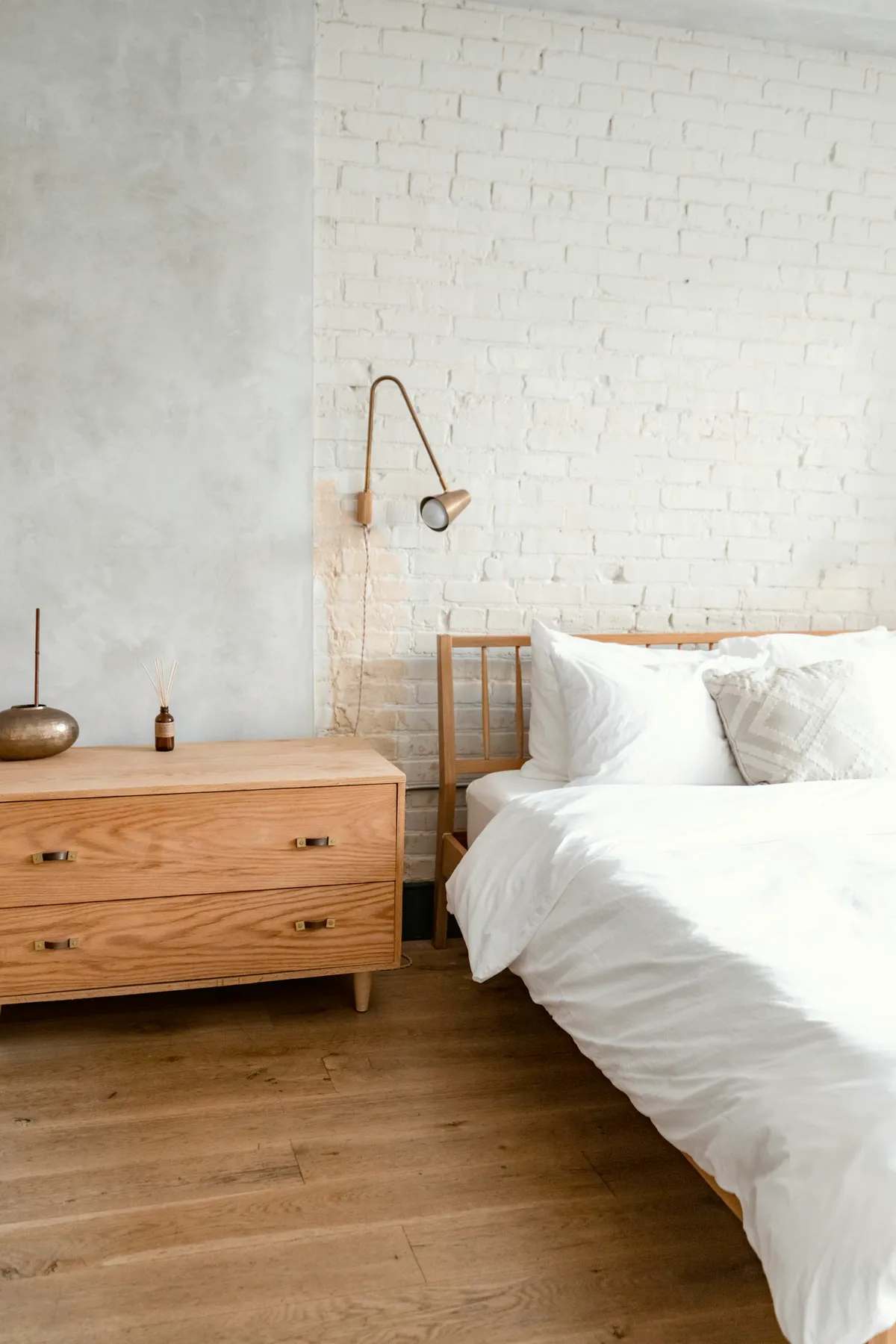 White brick room with an oak chest and a reading light