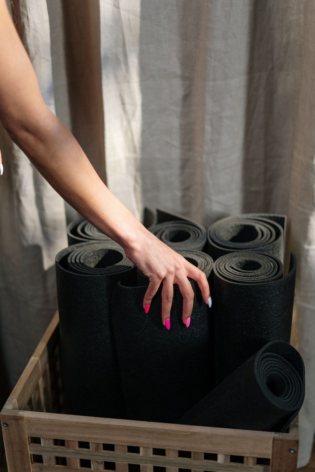 Hand choosing a mat from a wooden basket in the studio