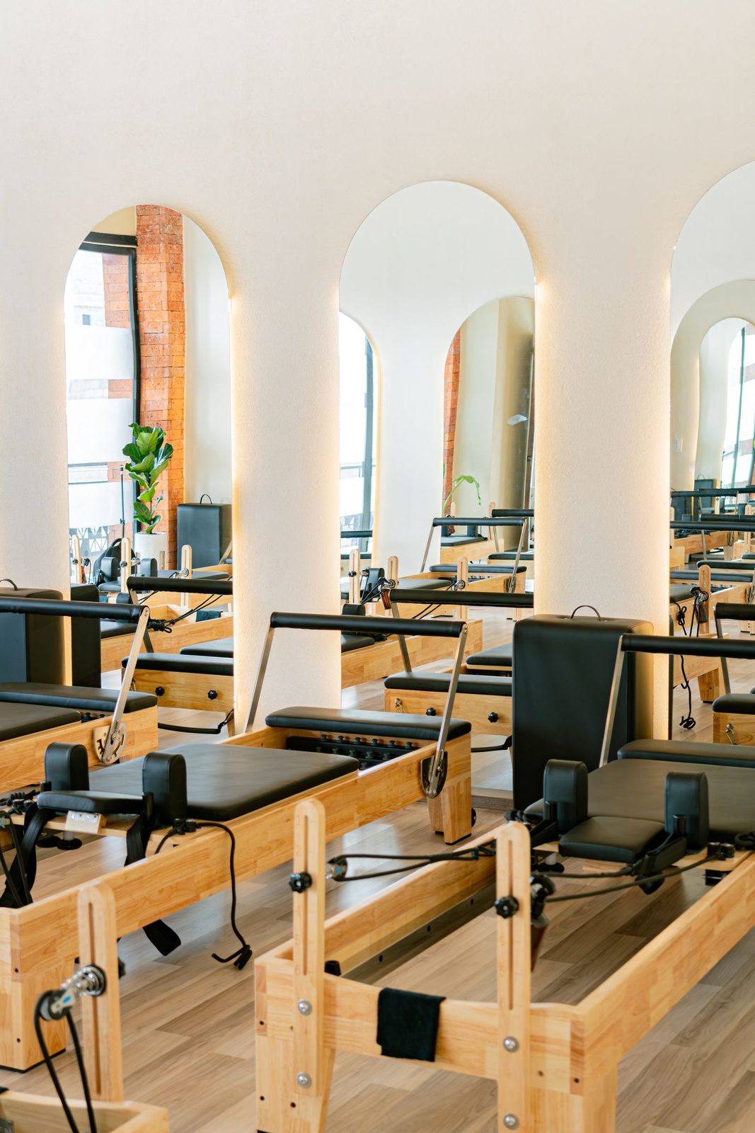 Bright reformer pilates studio with arched mirrors and wooden reformers