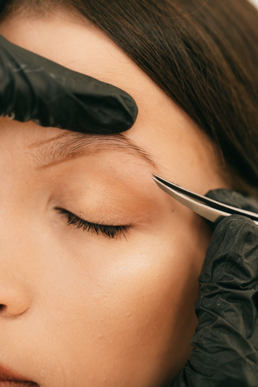 Close-up of an eyebrow being shaped with tweezers