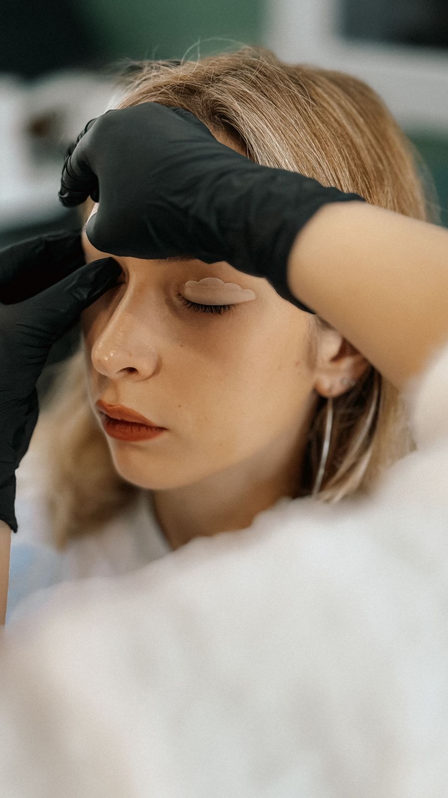 Gloved hands working on a client's brow