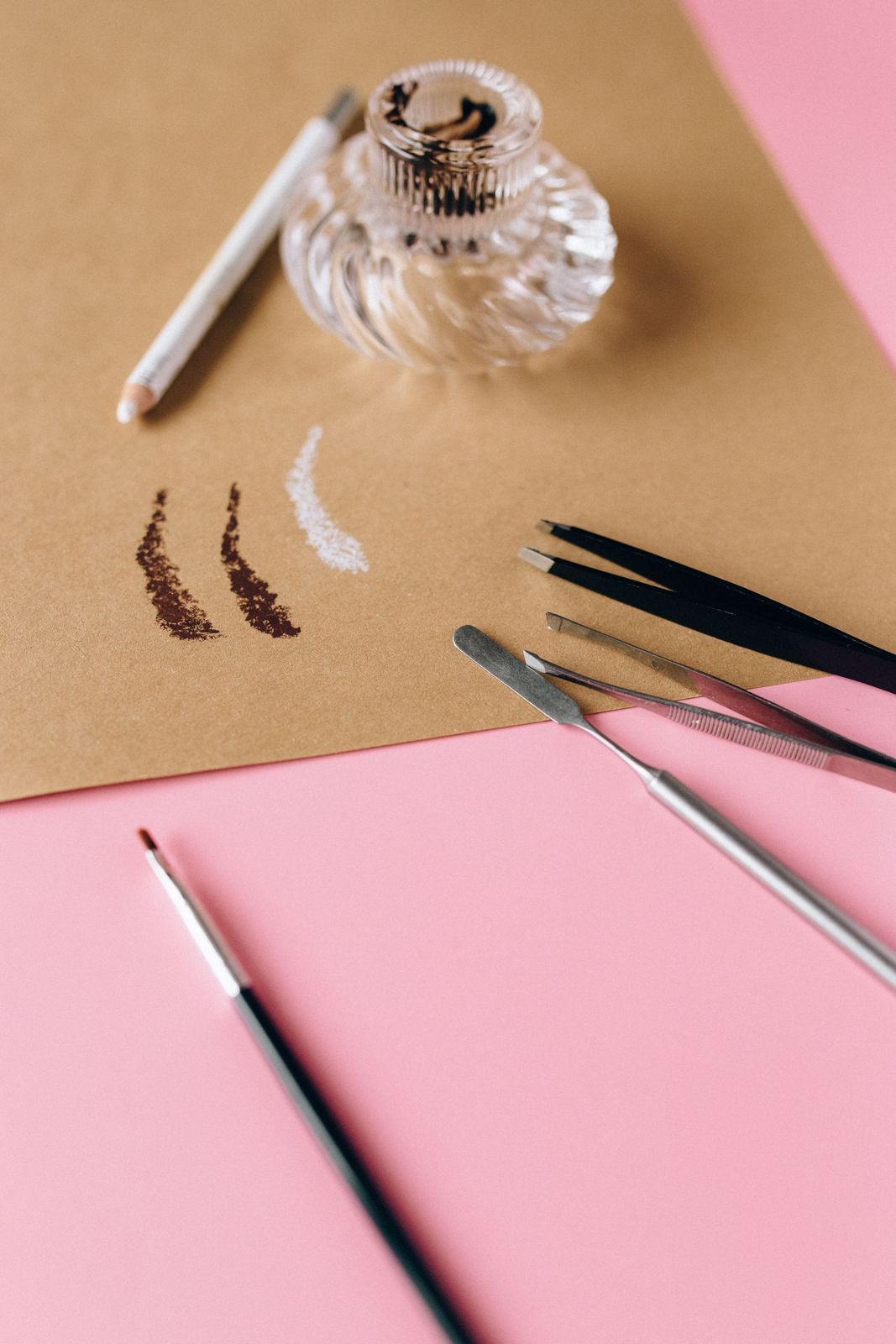 Brow pencils, tweezers and pigment swatches on paper