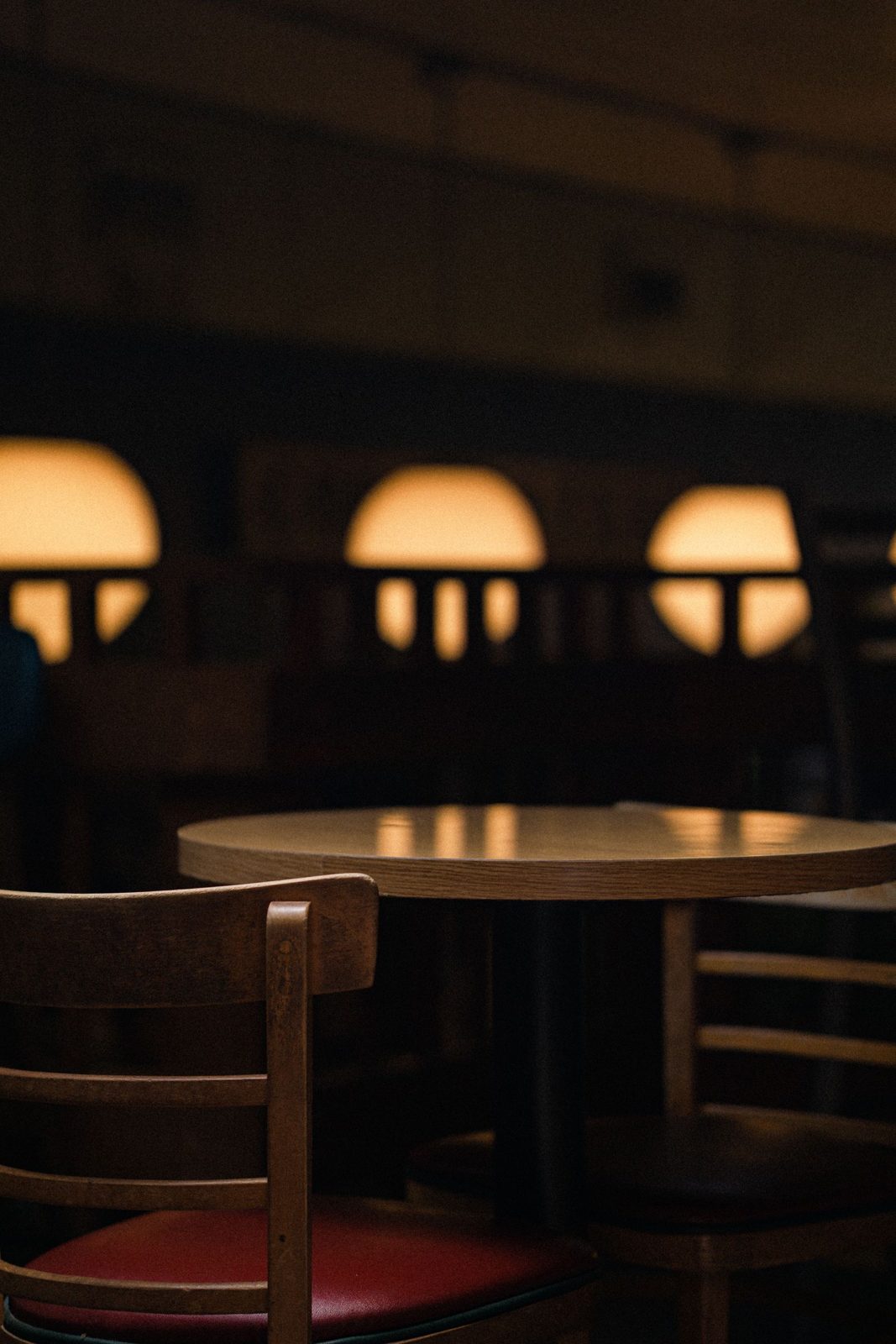 Wooden chairs and a round table under glowing globe lamps