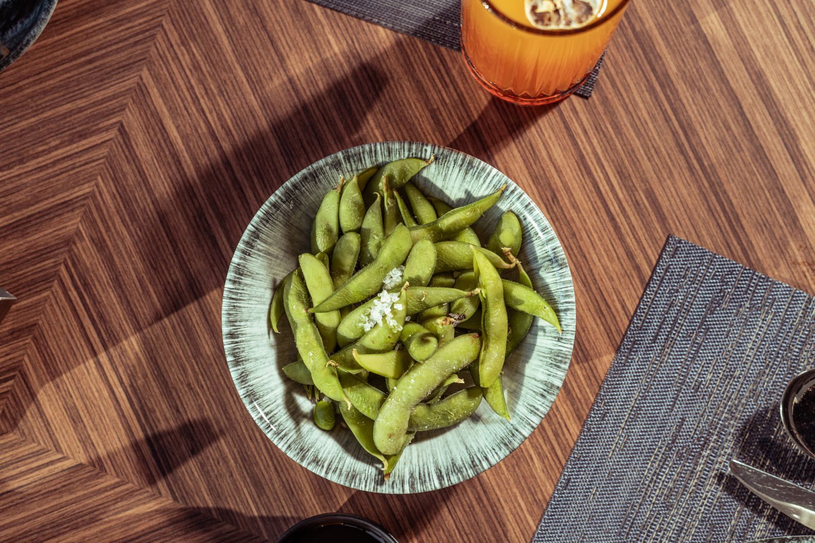 Salted edamame in a ceramic bowl on a wooden table