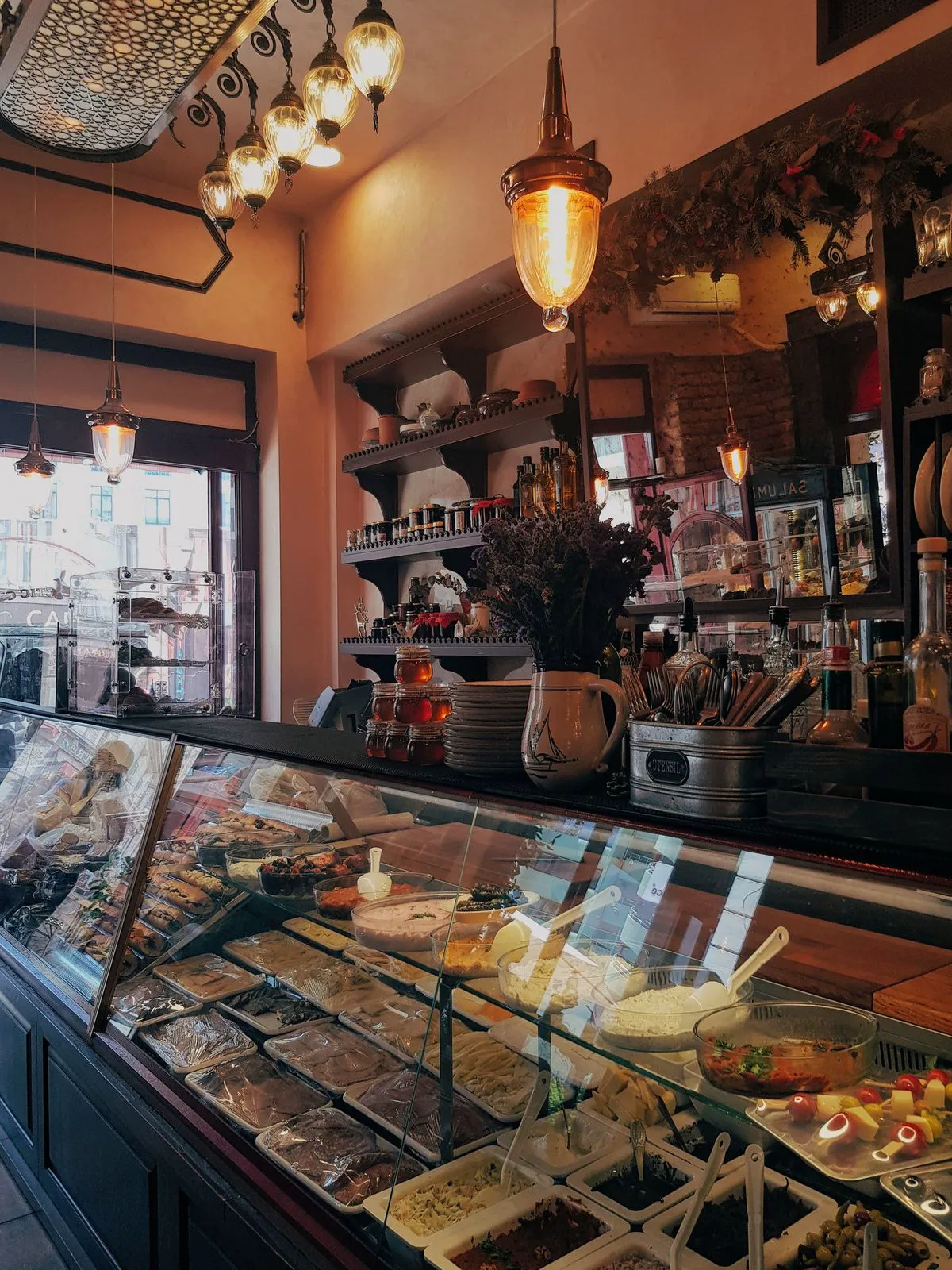 Deli case full of antipasti and spreads under warm pendant lights