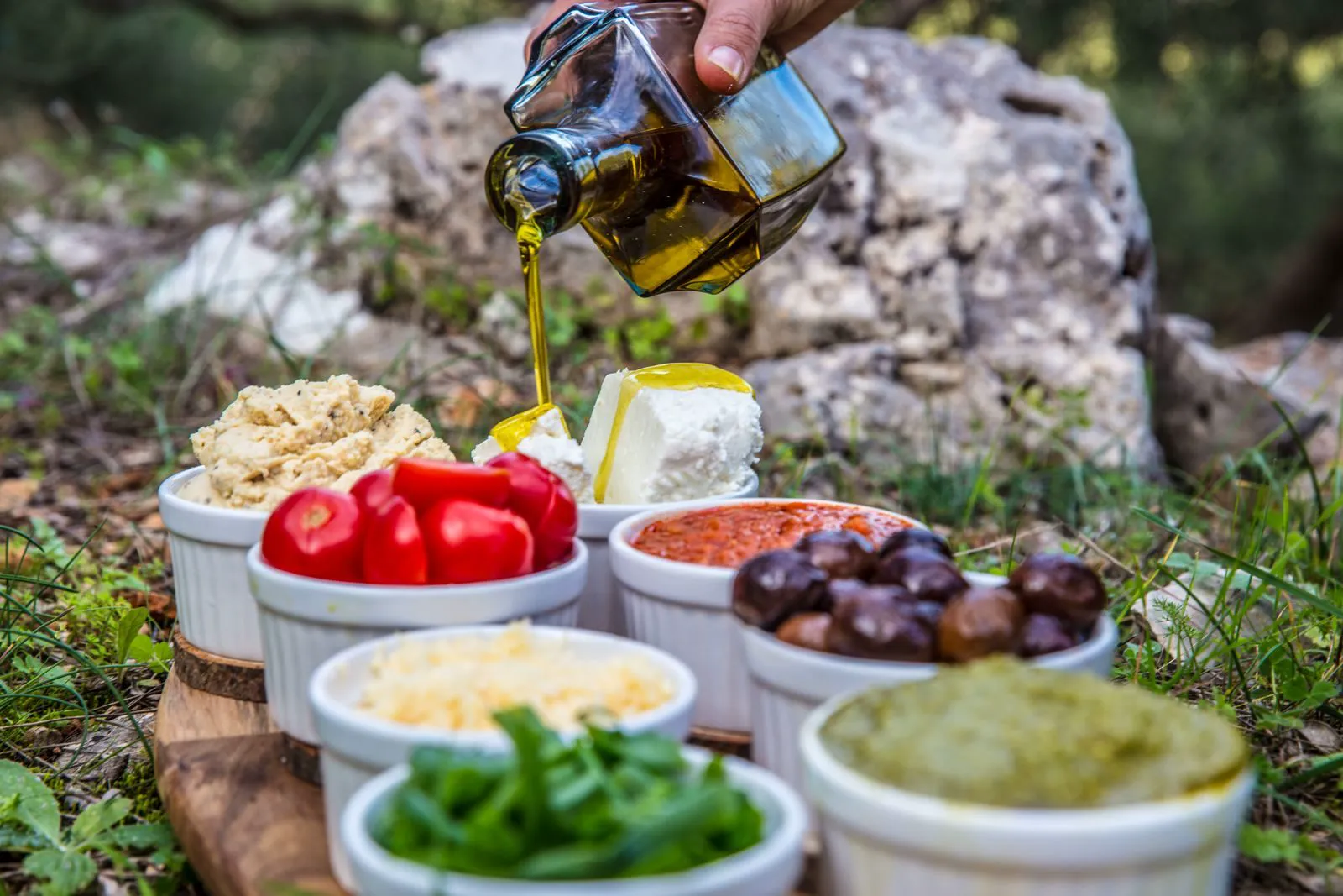 Small bowls of roasted peppers, feta and olives under olive oil