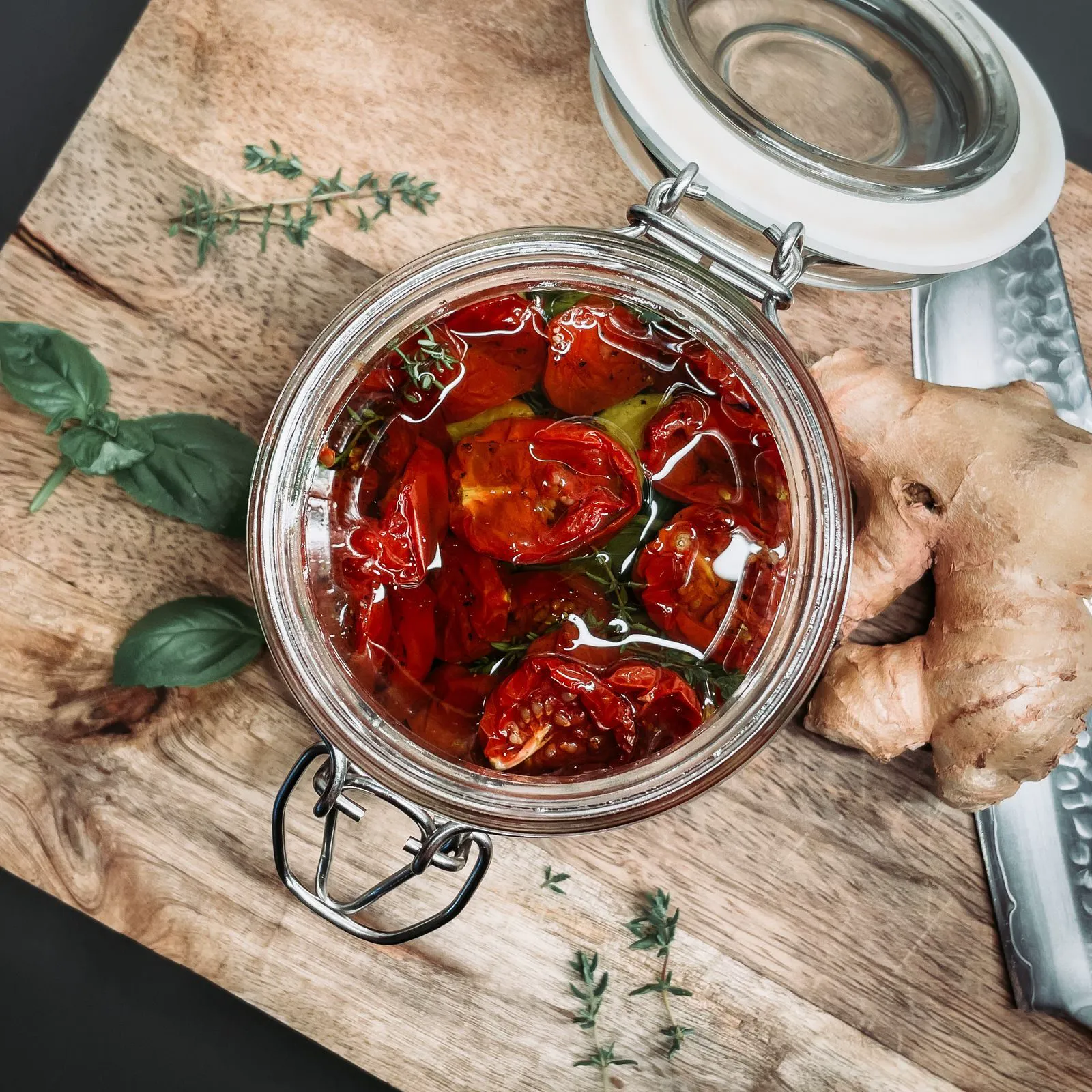 Glass jar of sun dried tomatoes in oil with herbs