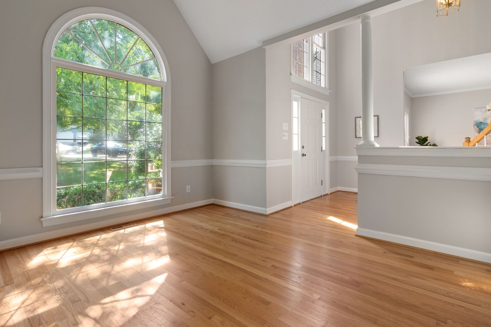 Sunny entry room with an arched window and a warm oak floor