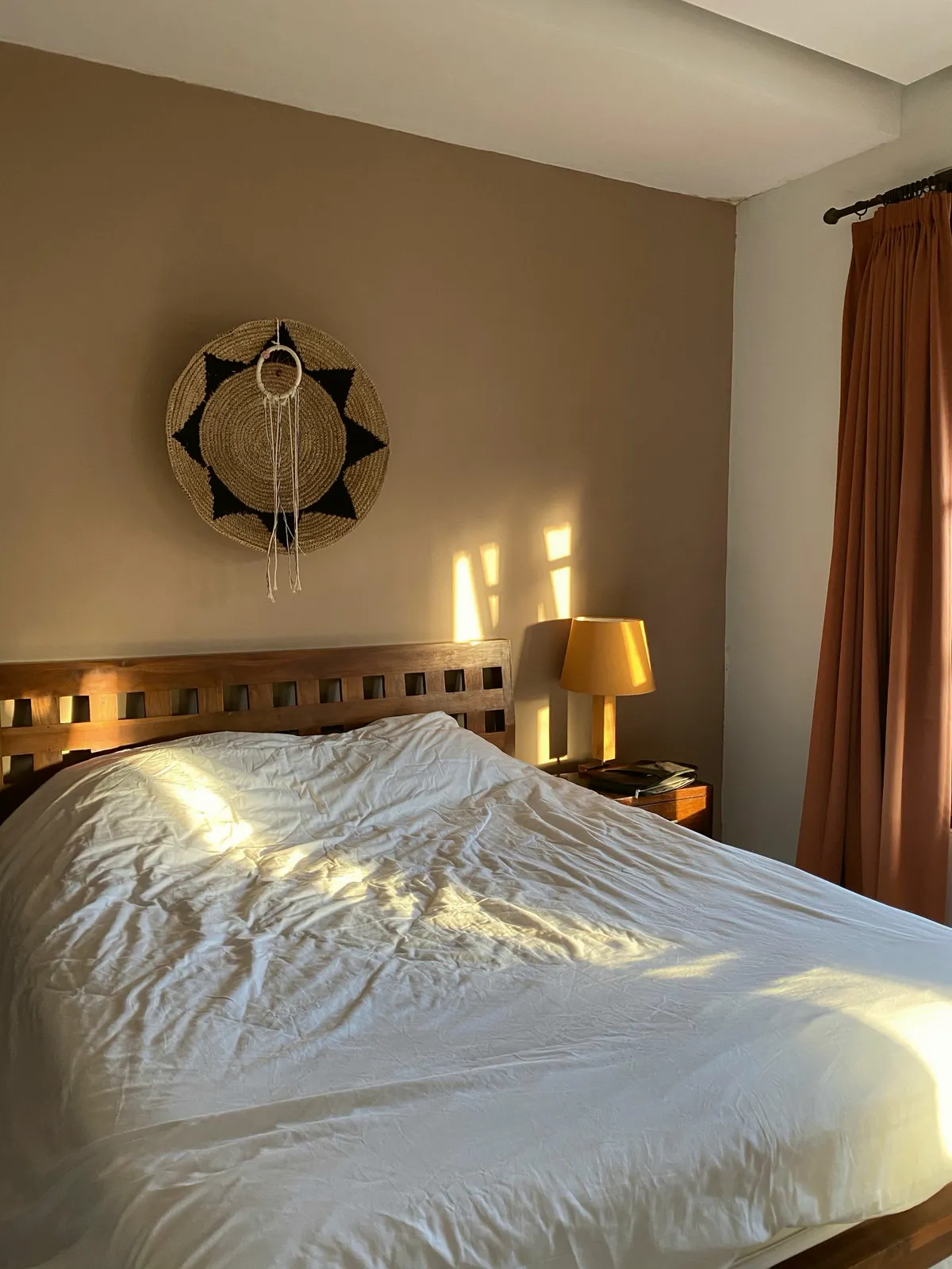 Linen bed in warm afternoon sun beside a brass lamp