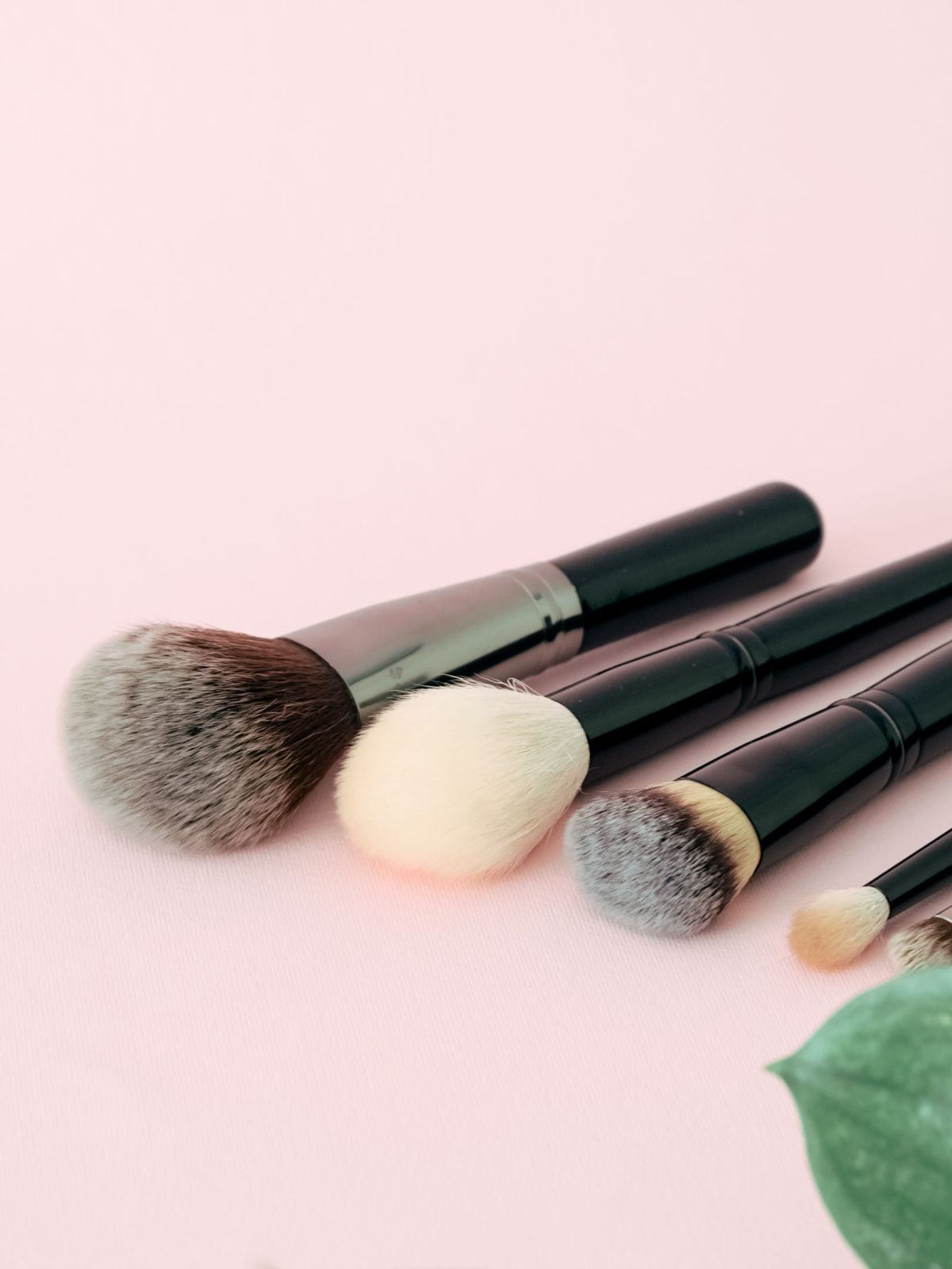 Makeup brushes on a pastel pink surface