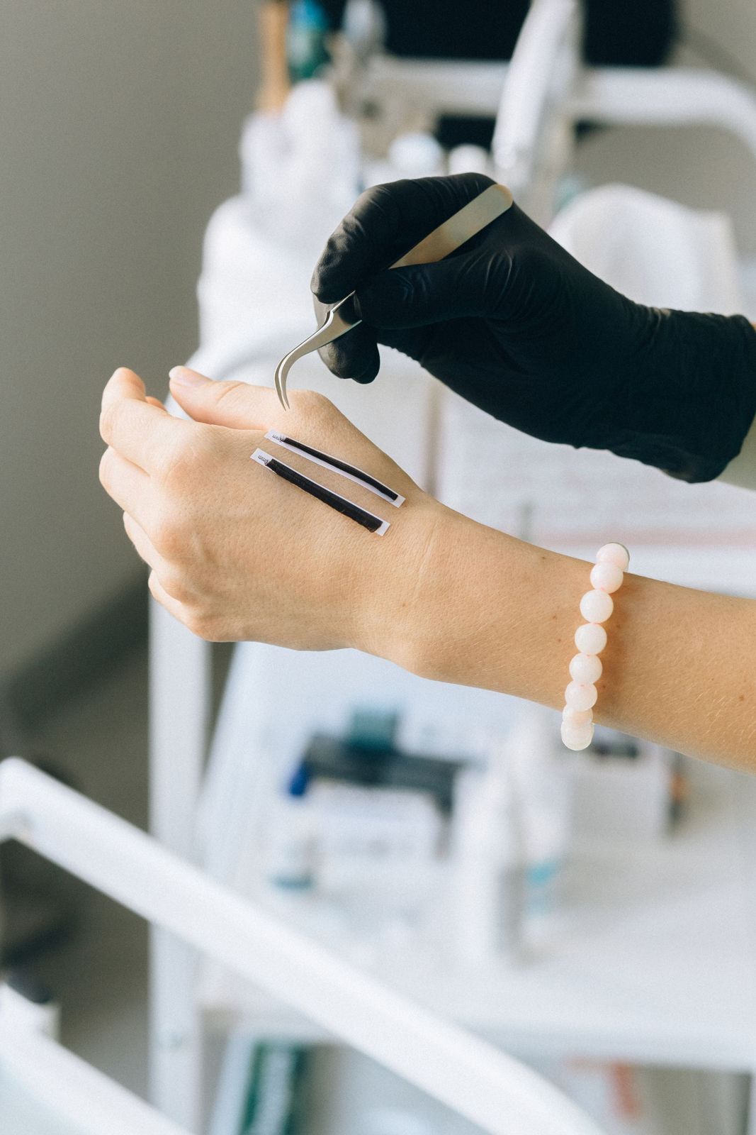 A gloved hand placing lash strips on the back of a hand