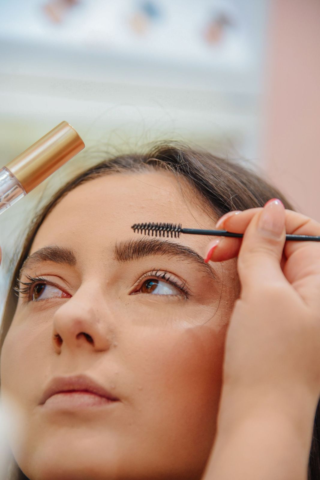 A brow being brushed upward with a spoolie