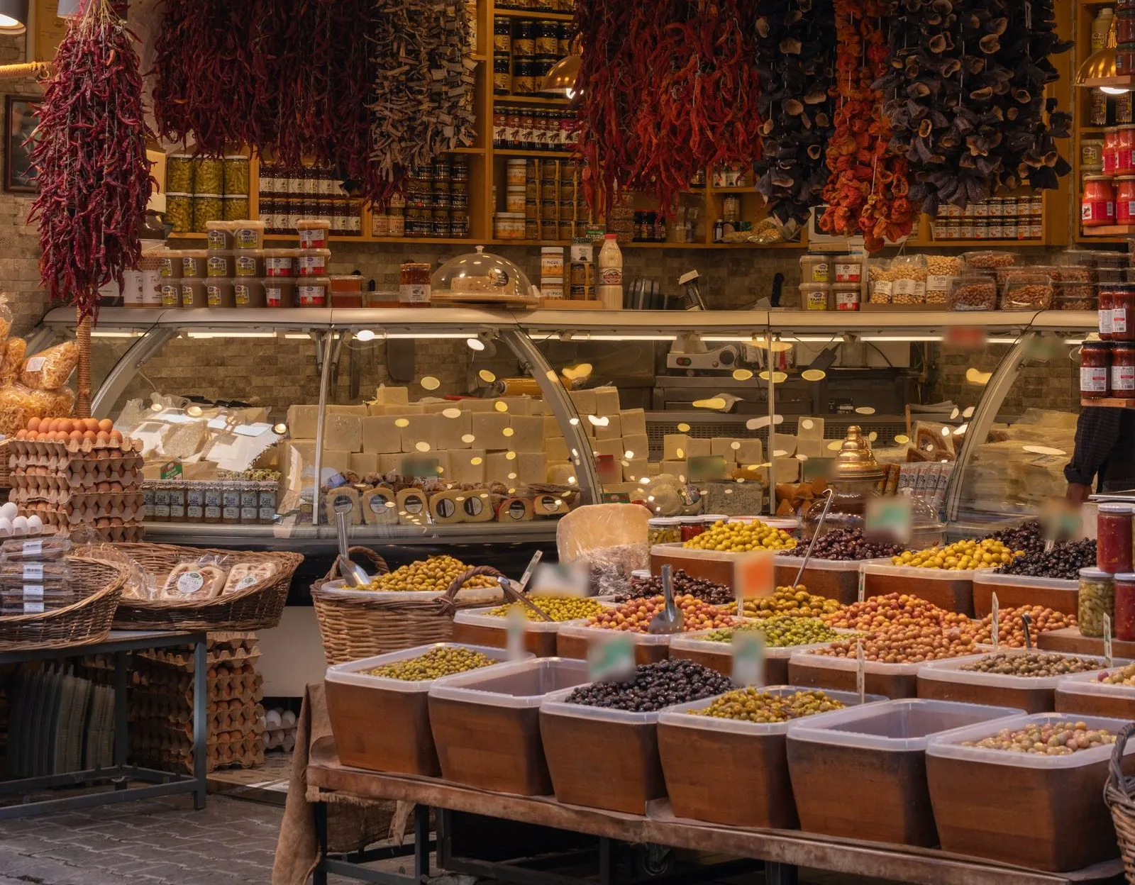 Deli counter with bins of marinated olives under warm lights