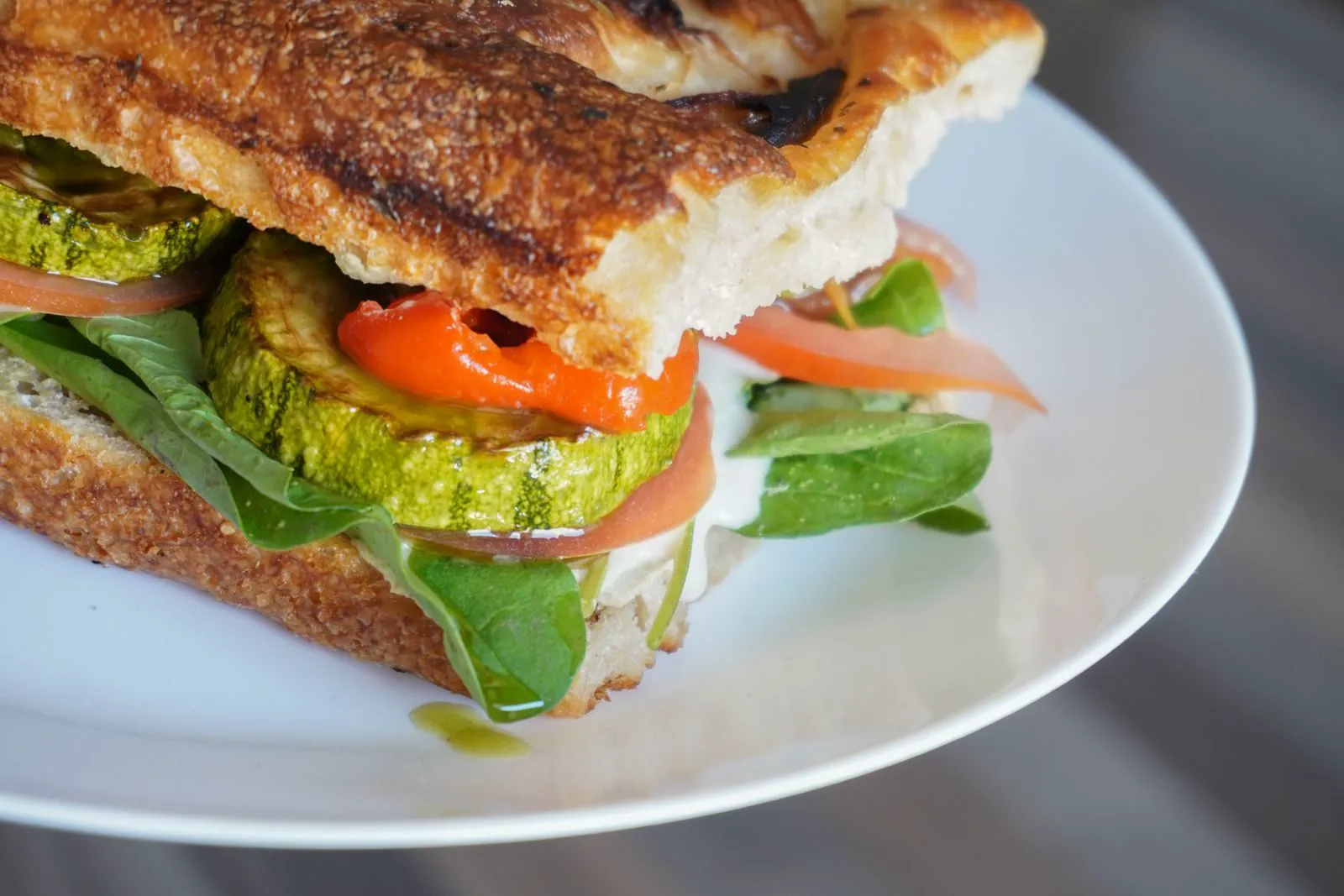 Focaccia sandwich with grilled zucchini, roasted pepper and greens