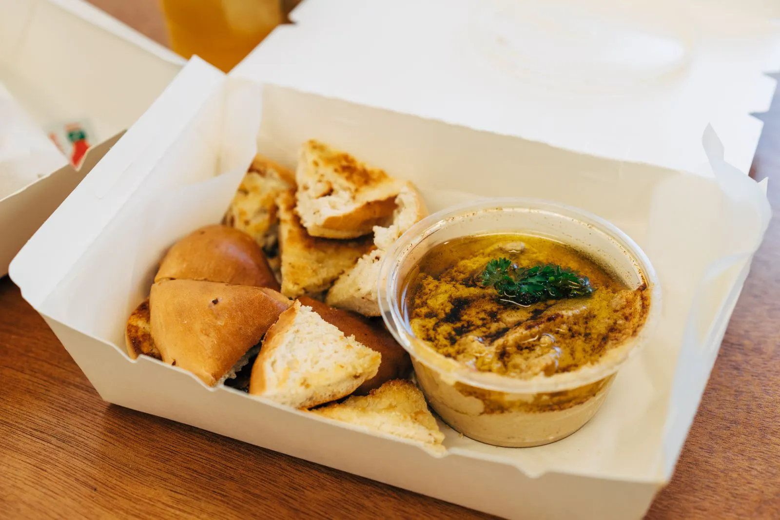Takeout box with hummus and toasted pita
