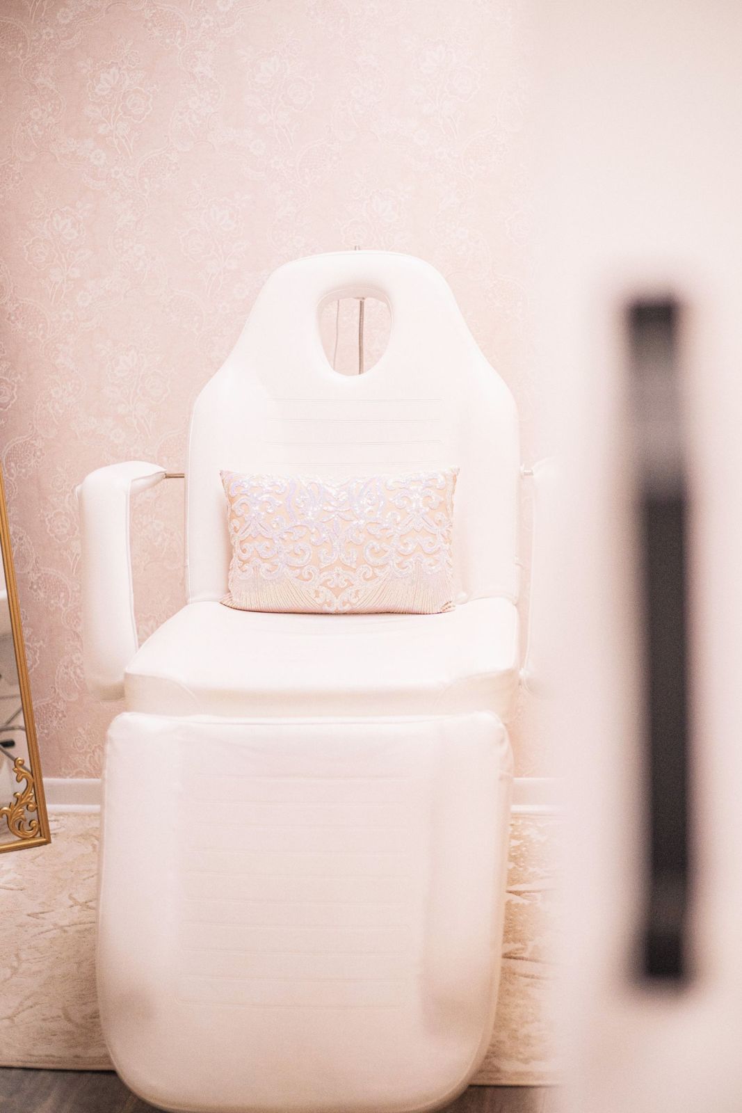 A white treatment chair with a soft cushion in a blush pink room