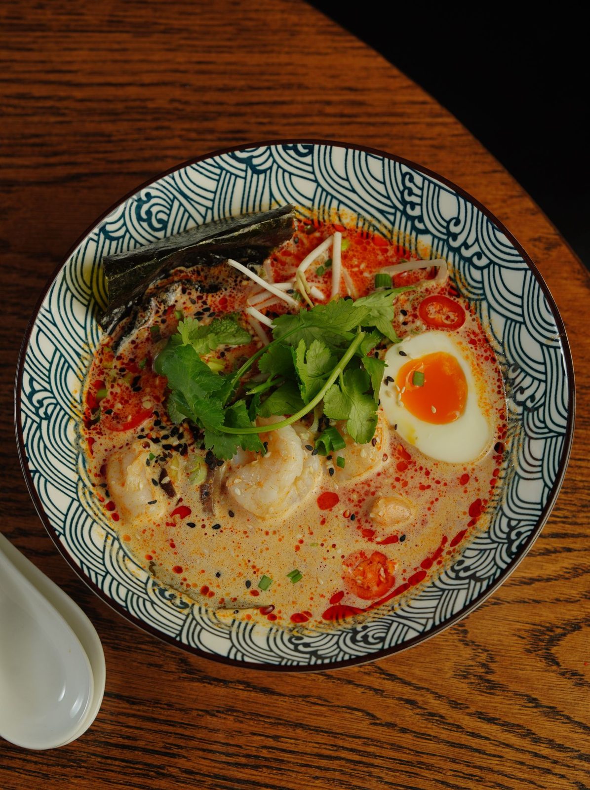 Spicy ramen with shrimp, cilantro and a soft egg in a patterned bowl
