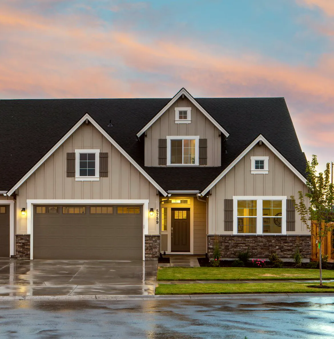 A gabled house at dusk with lit windows