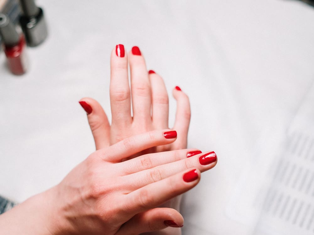 Hand mit sauber lackierten roten Nägeln